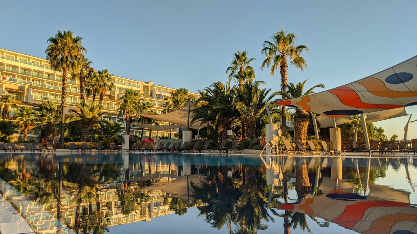 Ein luxuriöser Hotelpool spiegelt das umliegende Hotel und Palmen wider.